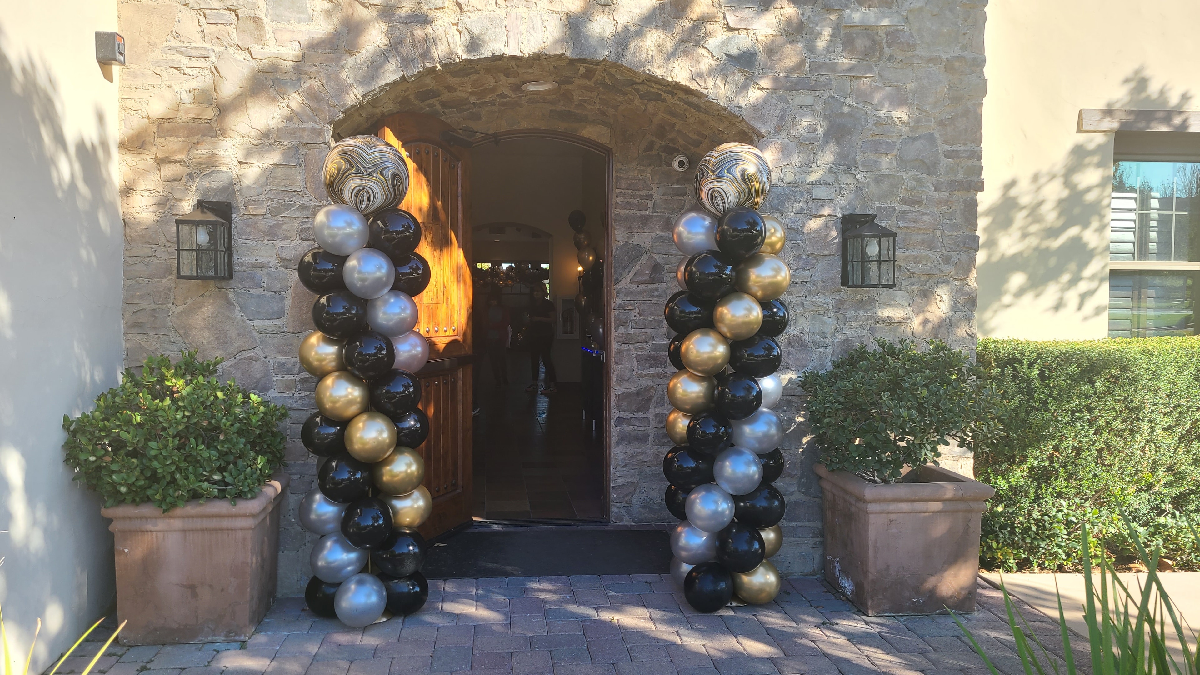 Metallic balloon columns at stone archway entrance